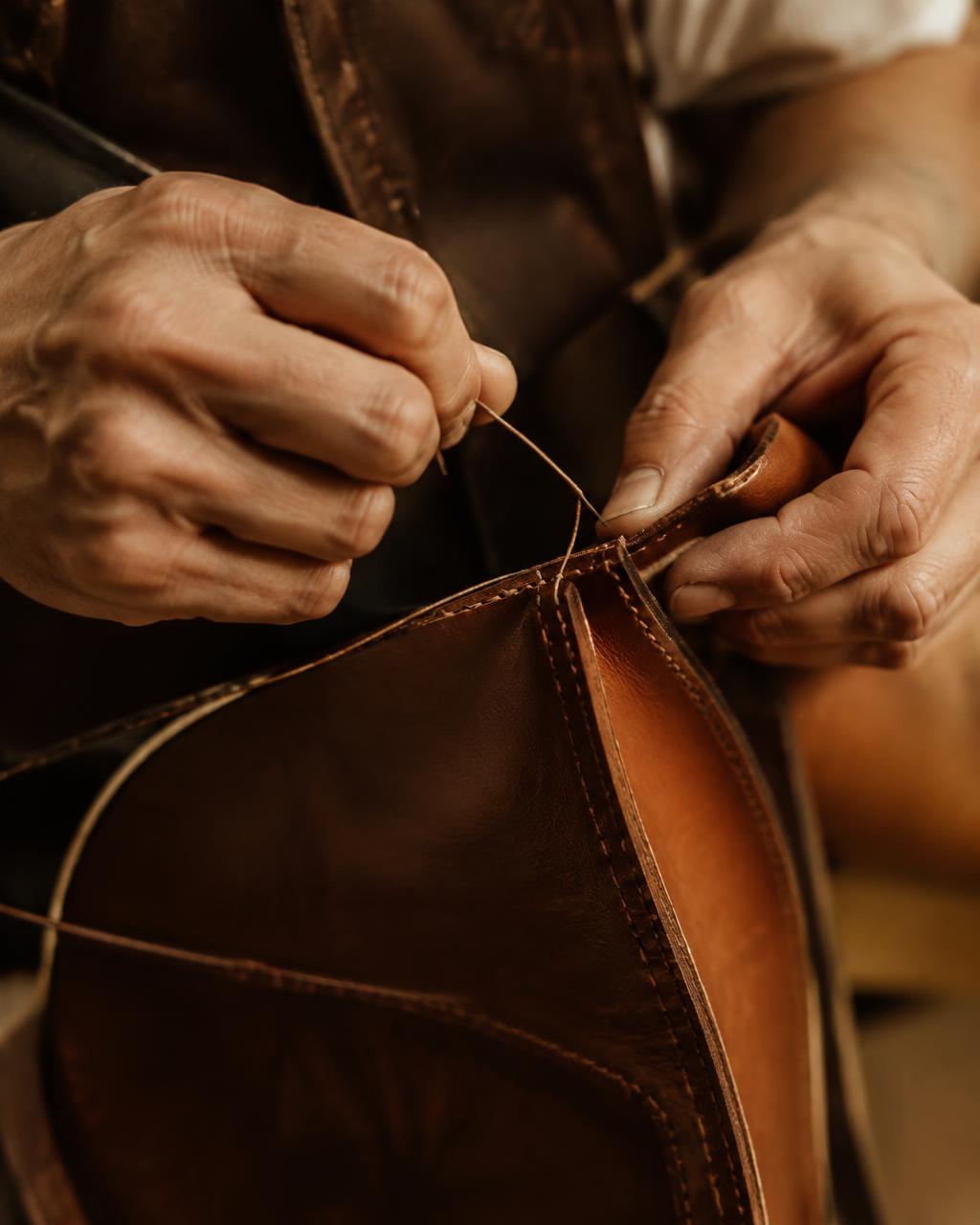 Manos artesanas cosiendo cuero